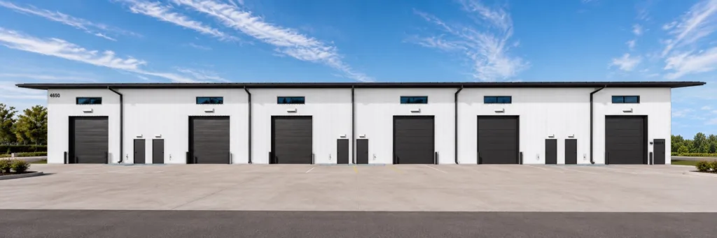 Rear of Building 1, numbered 4650: six dark overhead doors, service doors and high windows over a concrete apron