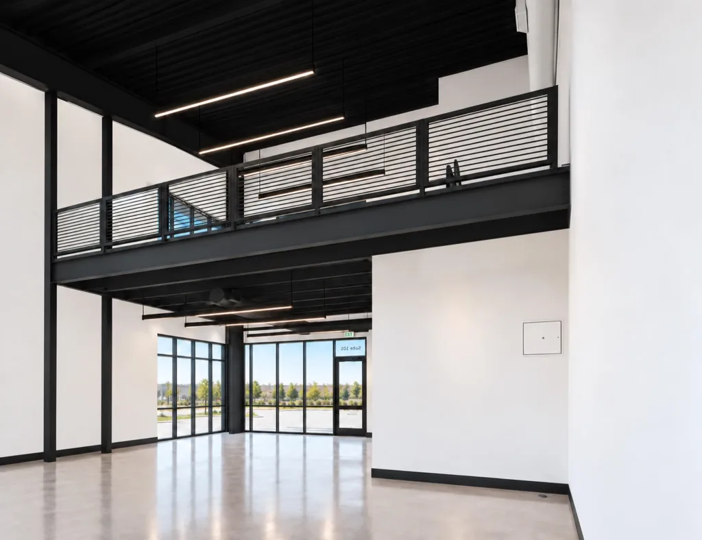 Double-height storefront windows beside a steel mezzanine, over polished concrete
